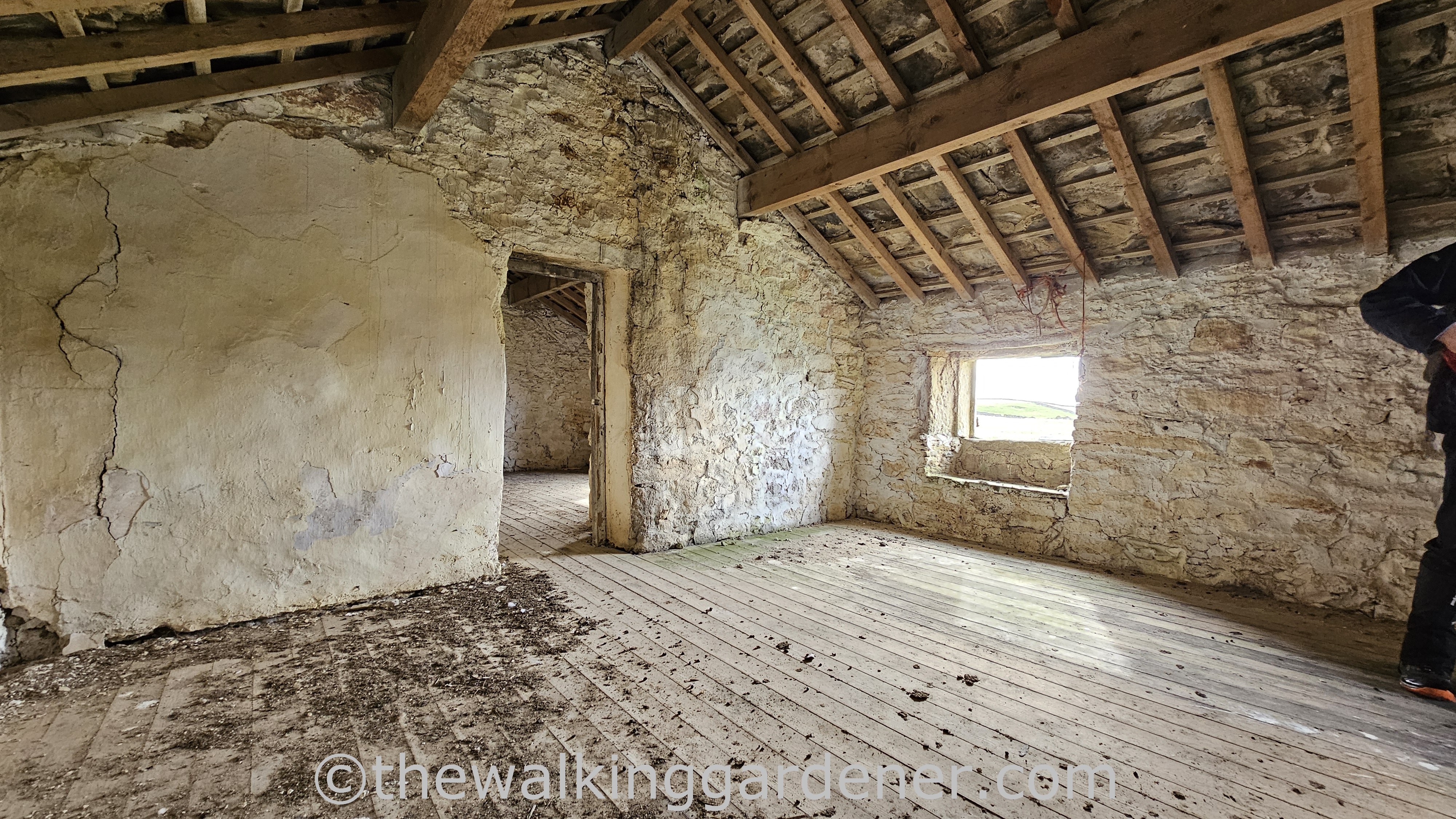 Interior of Bare House - a dilapidated farmhouse near Grassington featuring stone walls, wooden beams, and a wooden floor.